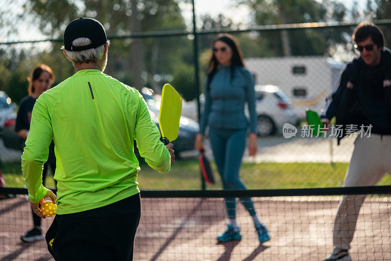 senior pickleball coach is teaching to two woman and one man pickleball player horizontal pickleball still